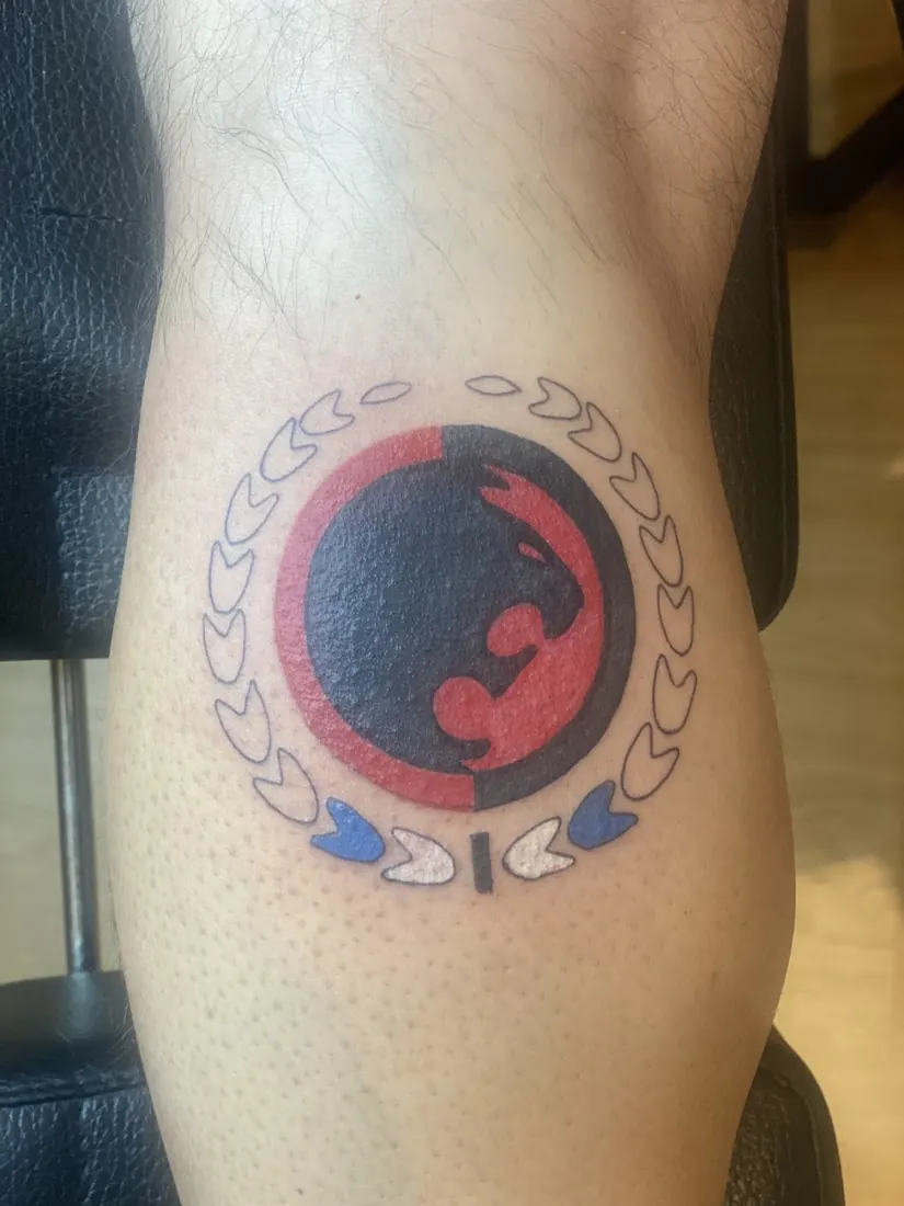 Round black, red and blue emblem tattoo on a calf