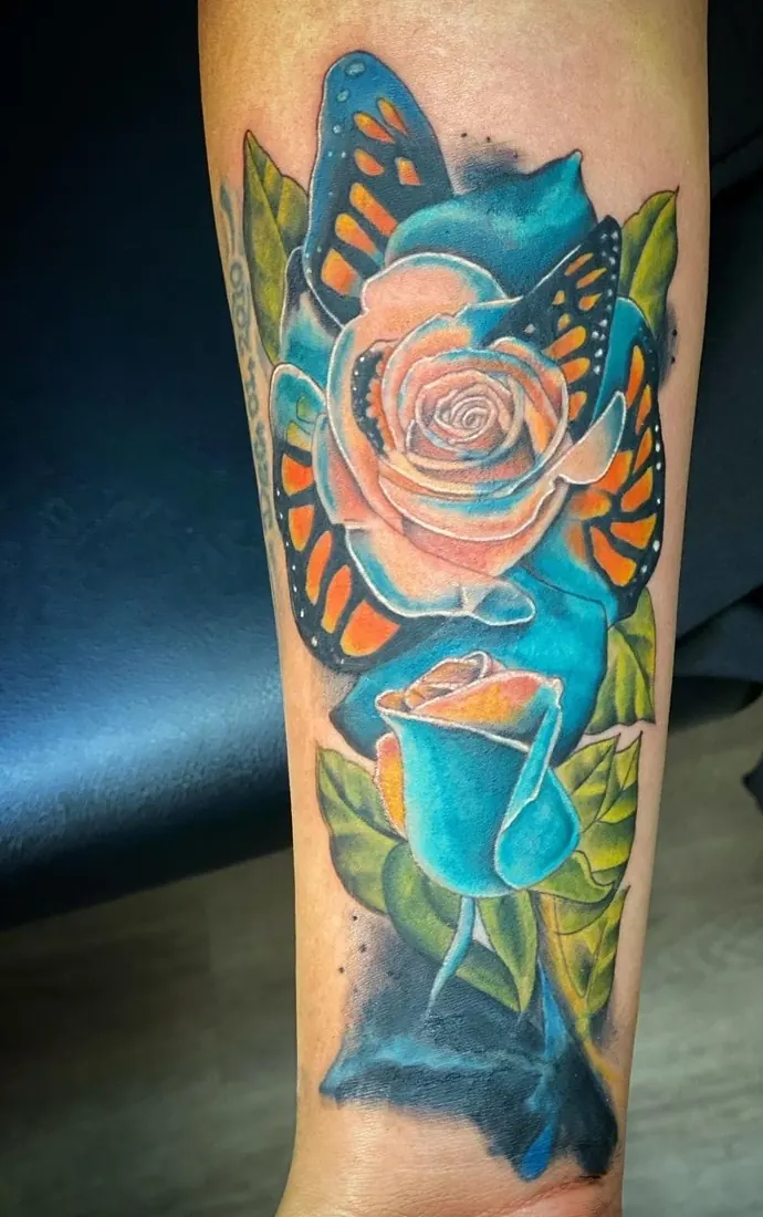 Blue butterfly and rose tattoo on a forearm