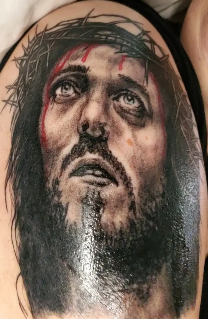 Black-and-grey portrait tattoo on an upper arm